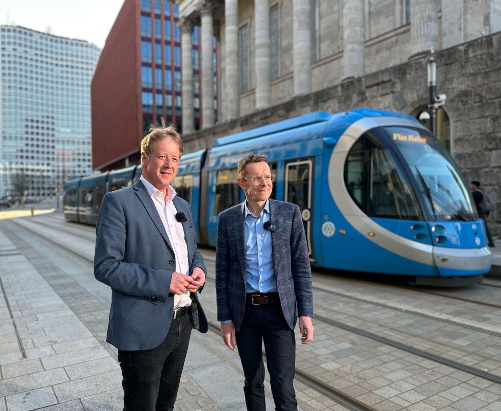 Bristow and Street stand in front of a train